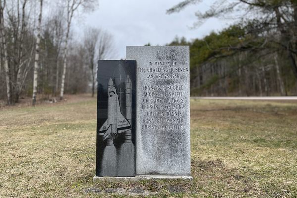 The Challenger Memorial at its prior home along Memorial Park. A block of South African granite serves as the surface for the illustration of The Challenger, while the other lists the names of the astronauts who perished in the explosion. 