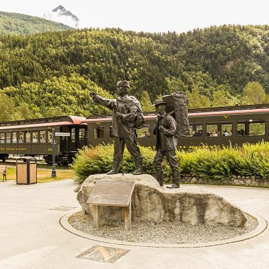 Skagway Centennial statue with the train in the background.