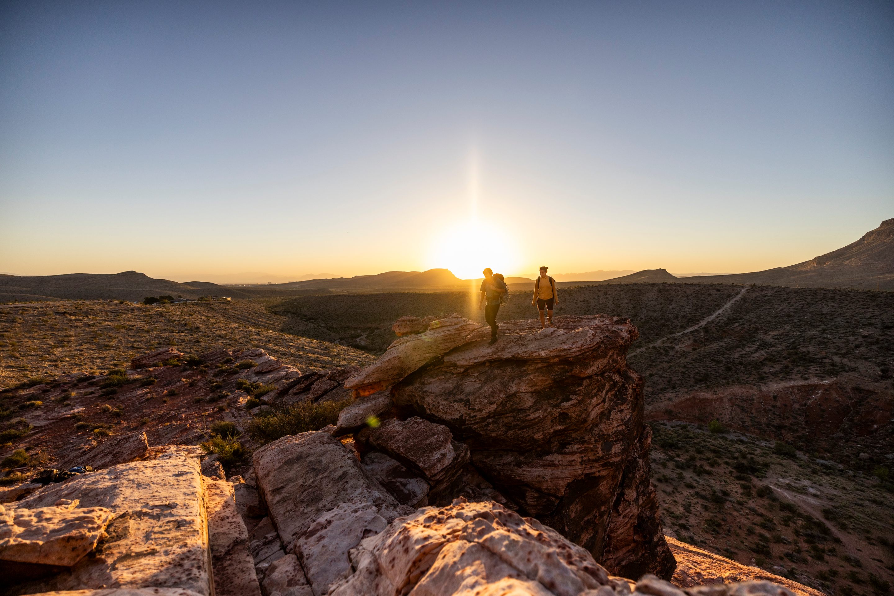 Two hikers in red rock canyon as the sun rises.