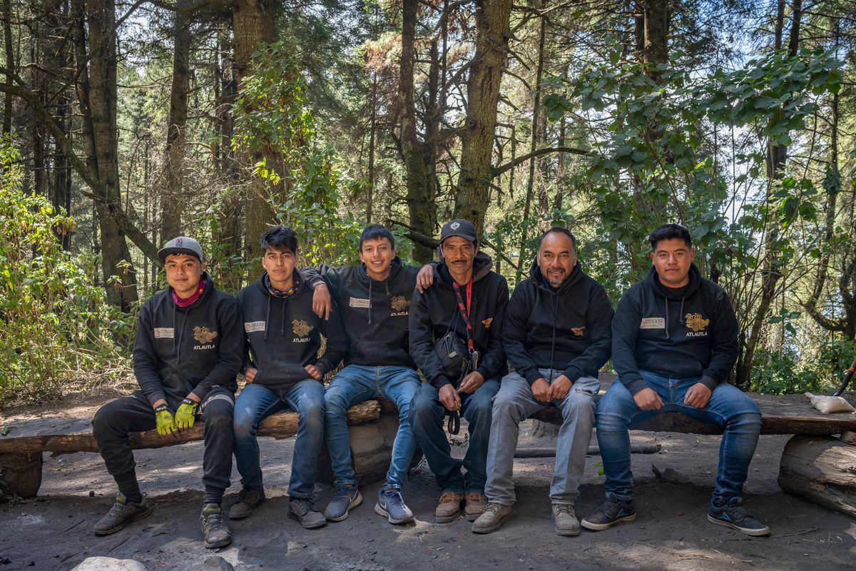 Members of the Atlautla Monitoring Brigade pose on a bench near the butterfly colonies in Joya Redonda. Director Eduardo Carrillo sits fourth from the left; next to him, on his right, is David Bautista.