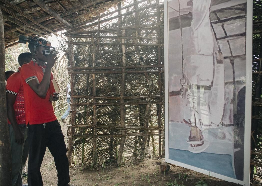 A visitor seeing Luc Tuymans' <em>Mwana Kitoko</em> through Carsten Holler's Upside Down Goggles in one of the Kisendus. 