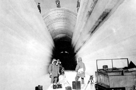 Camp Century trench construction in 1960. Caption reads "Metal arch forms being emplaced over undercut trench."