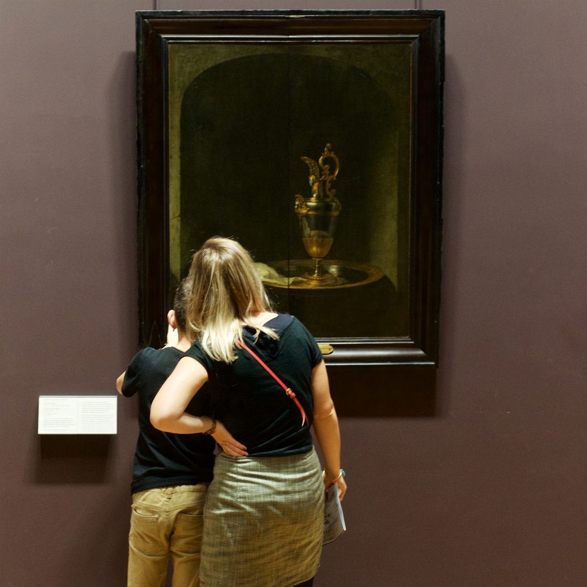 Two guests touch Gerrit Dou's "The Silver Ewer," on display at the Louvre.