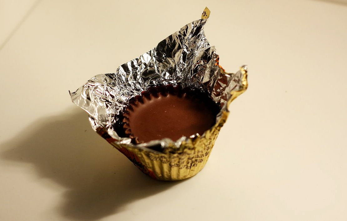 Unwrapping a Reese's Peanut Butter Cup.
