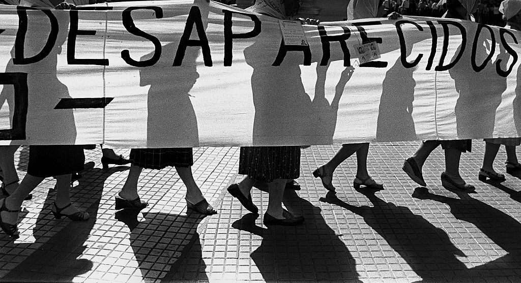 Members of the 'Madres de Plaza de Mayo' human rights organization, hold a banner claiming for their missing sons and daughters as they walk in front of the Presidential Palace, c1980, Buenos Aires.