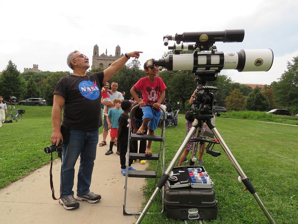 As part of a summer movie showing of <em>Buzz Lightyear</em> at the University of Chicago, Joe Guzman, known to many as "Astronomer Joe," sets up his telescope for locals to peer into the night sky.