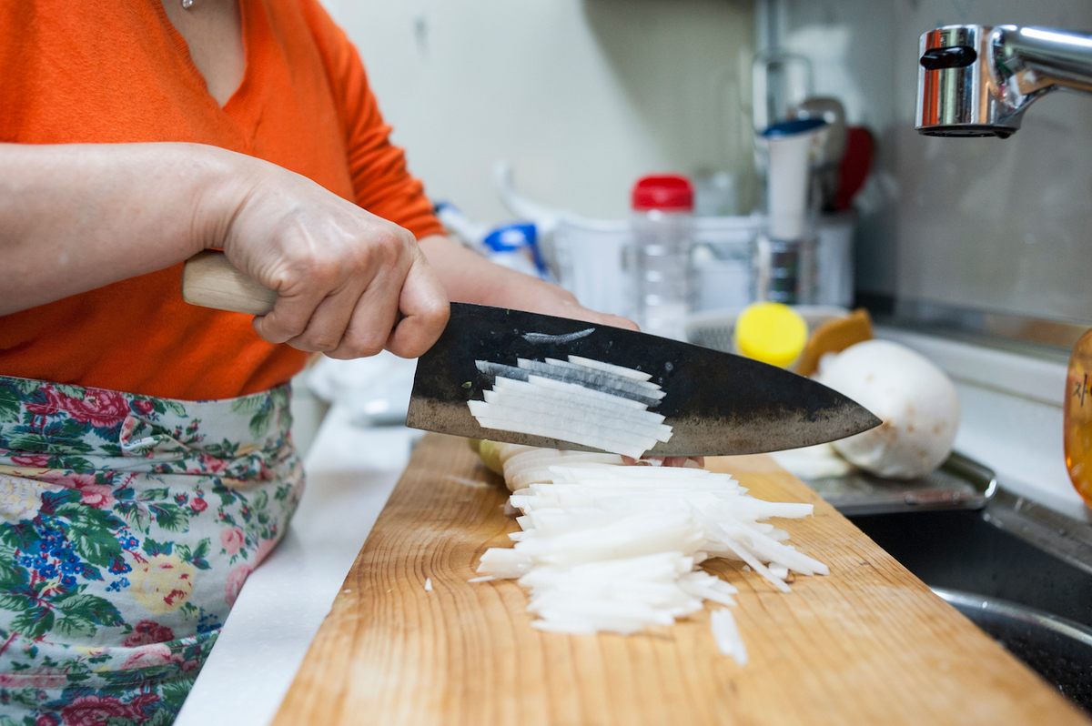 Lee chops daikon with a sturdy knife, called a "Chosun" knife, which she says allows for the radish bits to fall off nicely.