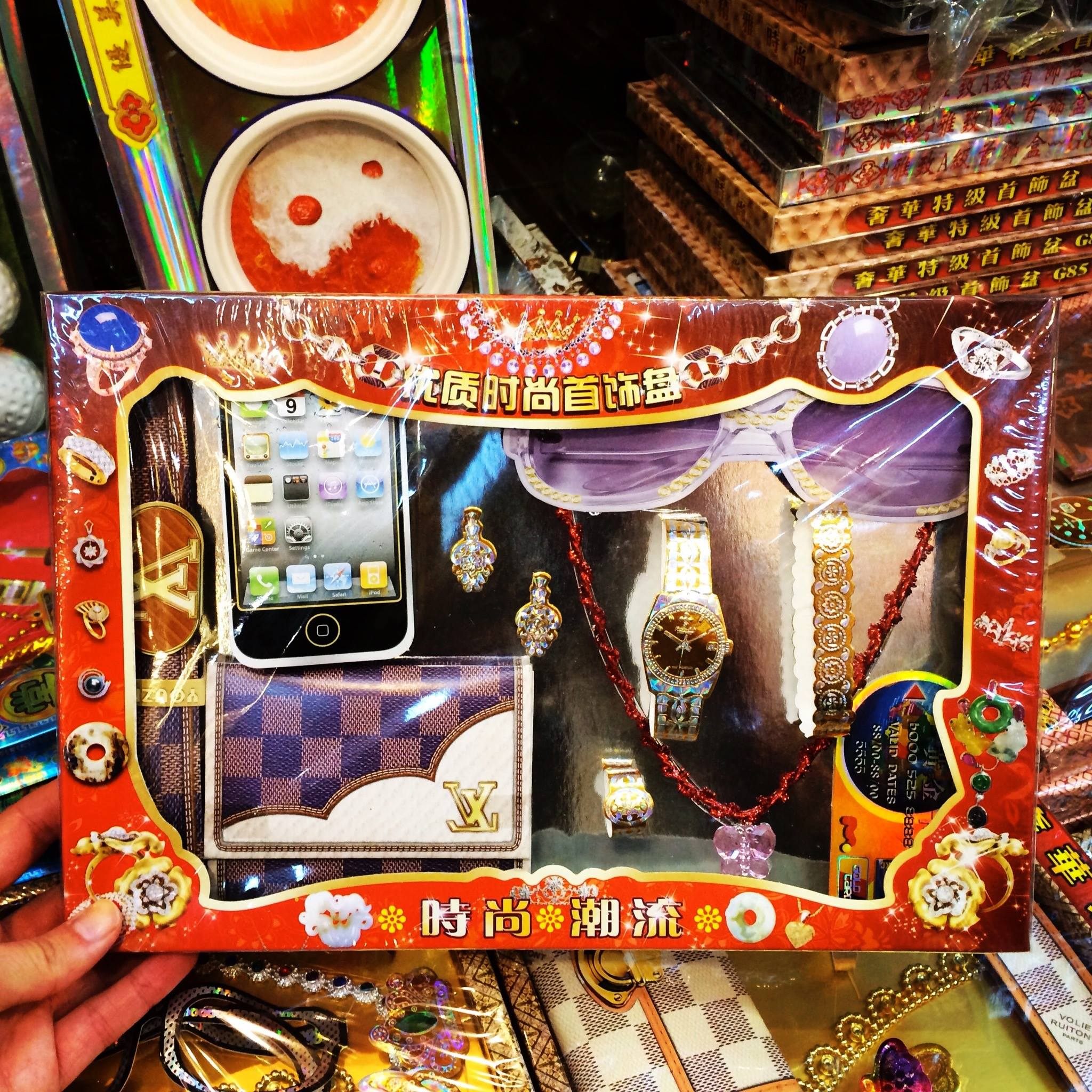 A box of ghost effigies containing an iPhone, a luxury wallet, and a watch. It is believed that ghosts should enjoy modern comforts in afterlife. 