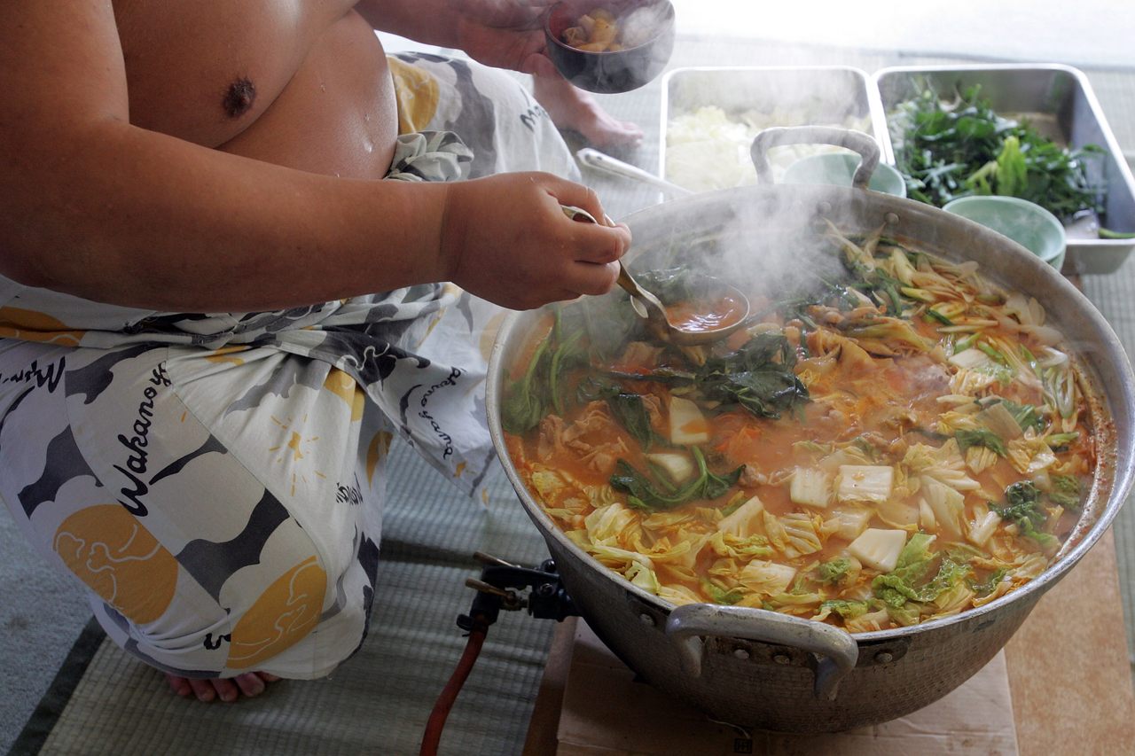 A sumo wrestler dishes up <em>chanko-nabe</em> during a "Sumo Diet Campaign" event in Osaka, Japan.