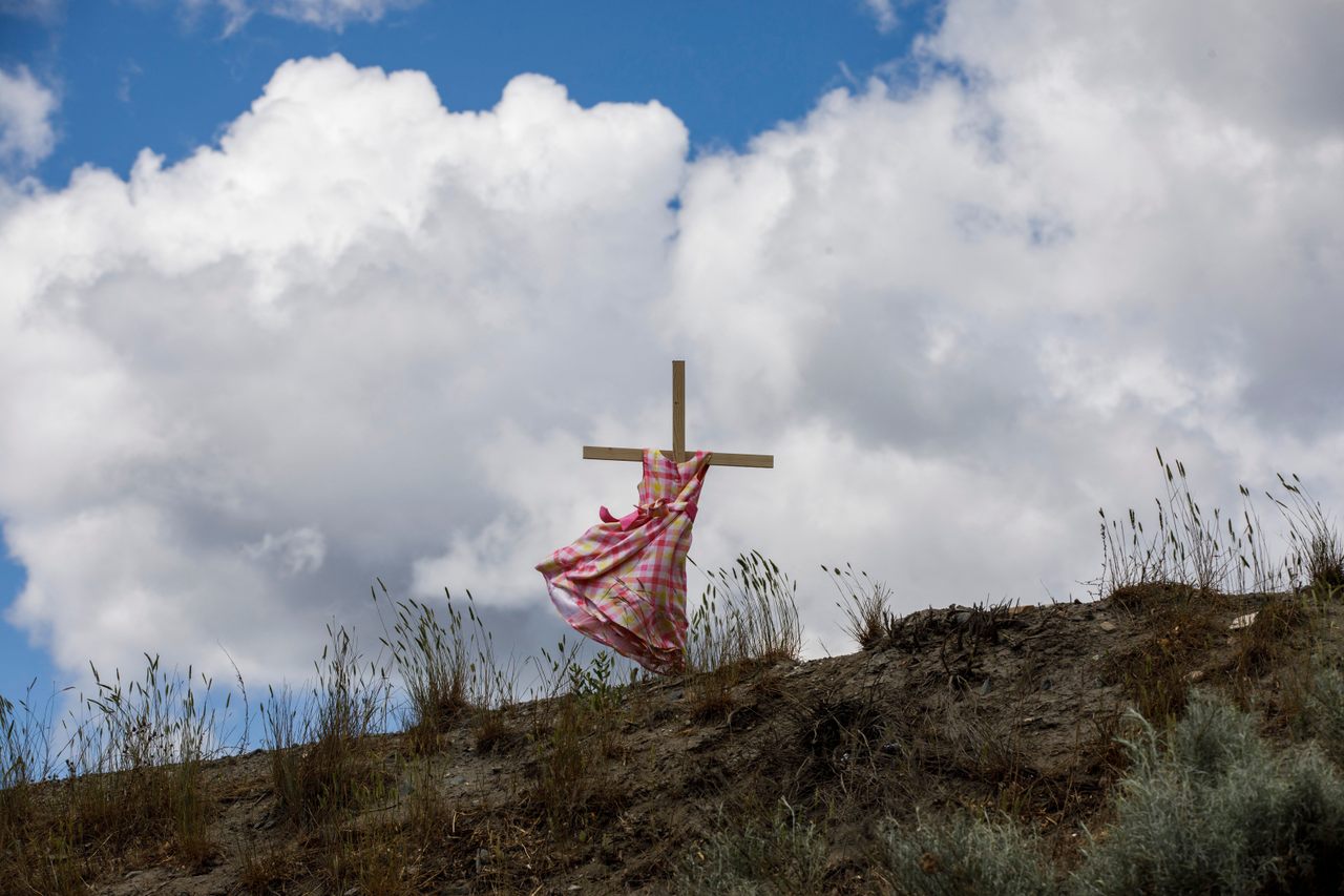 In British Columbia, a staked child’s dress blows in the wind near the former Kamloops Indian Residential School, where signs of unmarked children’s graves have been found.