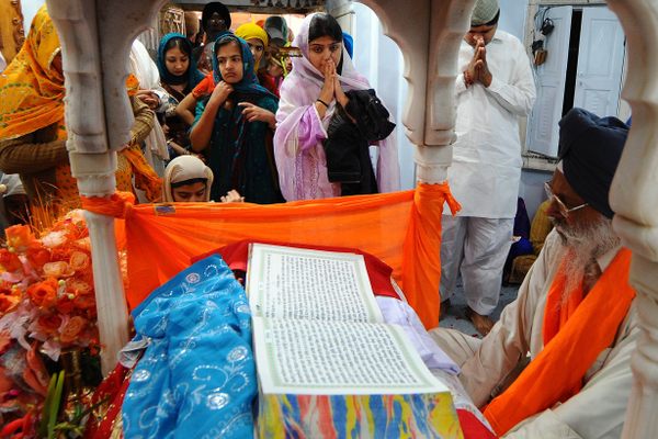 Pakistani and Indian Sikh devotees gather around a priest reading from the Sikh holy book to celebrate the birthday of Sri Guru Nanak Dev, in Nankana Sahib. 