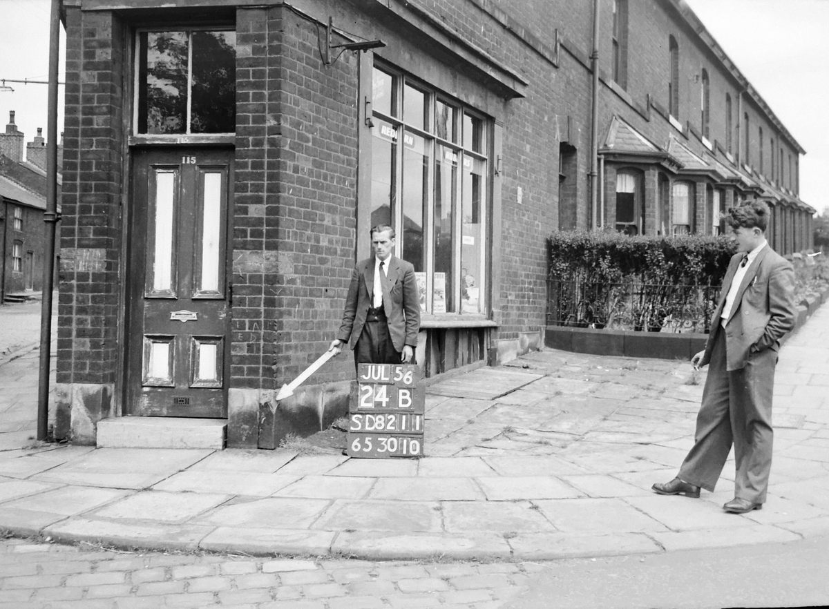 An Ordnance Survey worker does his duty as an onlooker stands by.