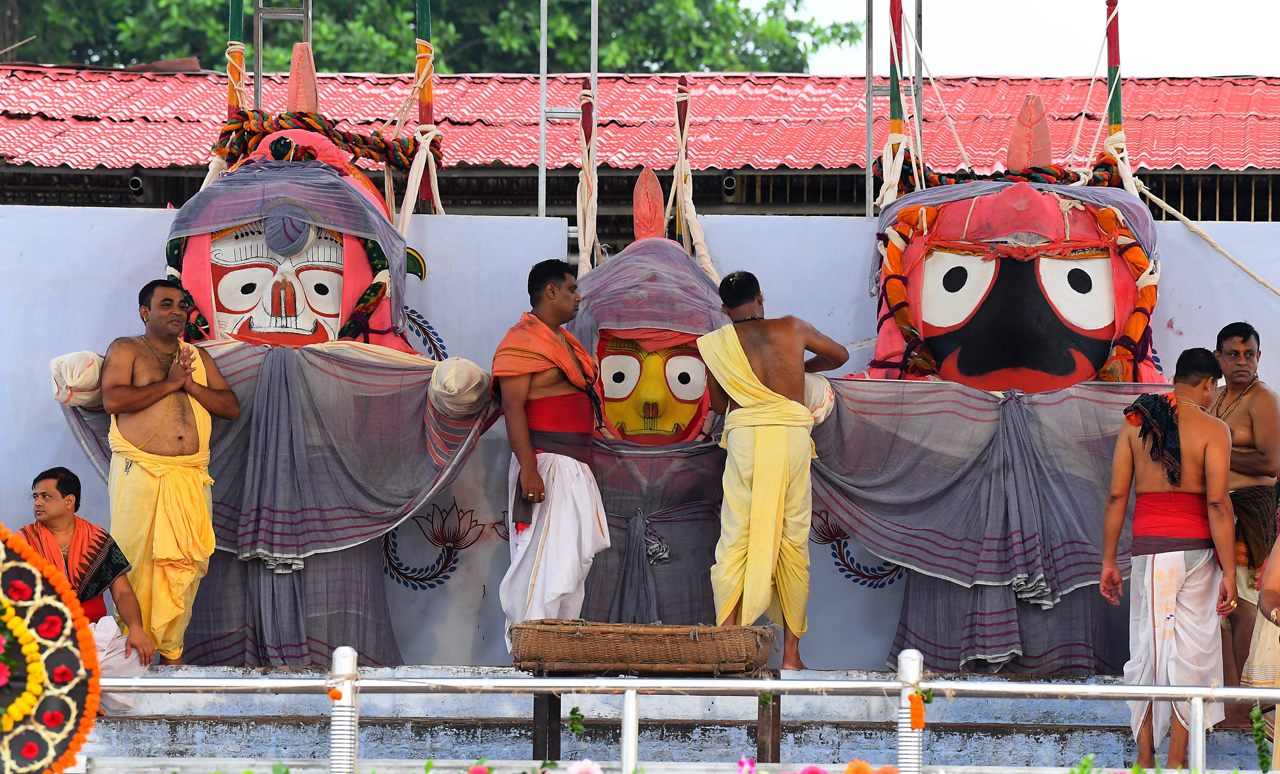 Temple attendants conduct the ritual bathing of the idols of (left to right) Balabhadra, Subhadra, and Jagannath in Puri on June 6, 2020. 
