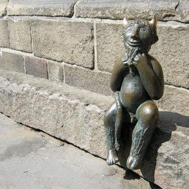 The devil sits on the stone slab, smiling at passers-by