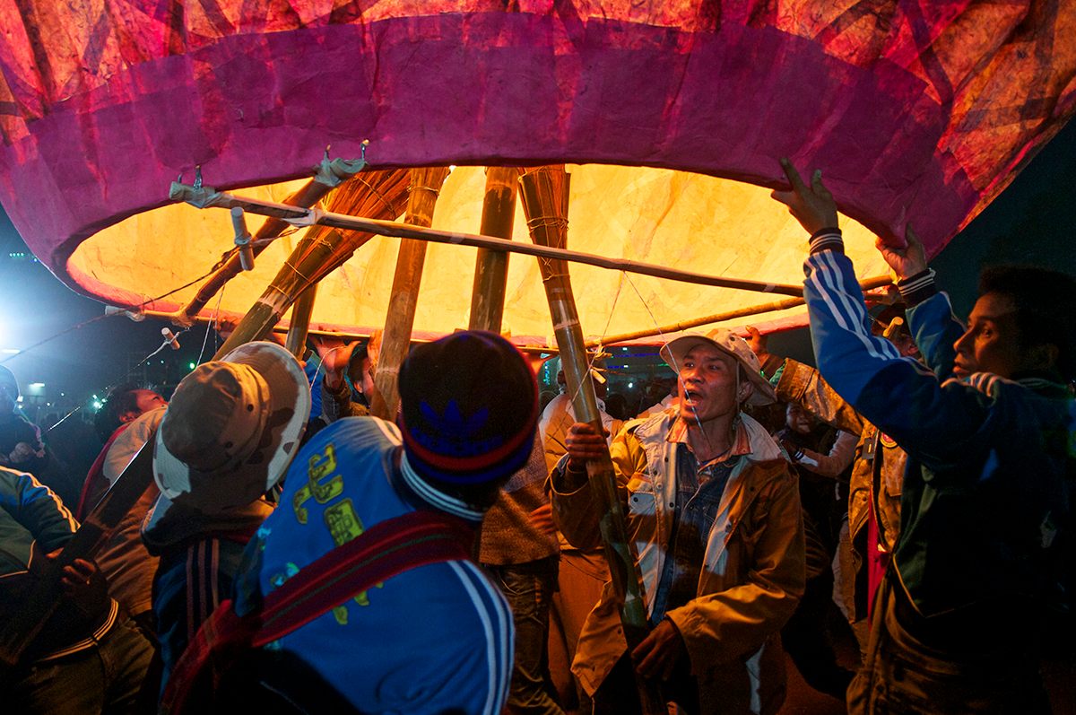 Team members hold torches to set a balloon afloat.