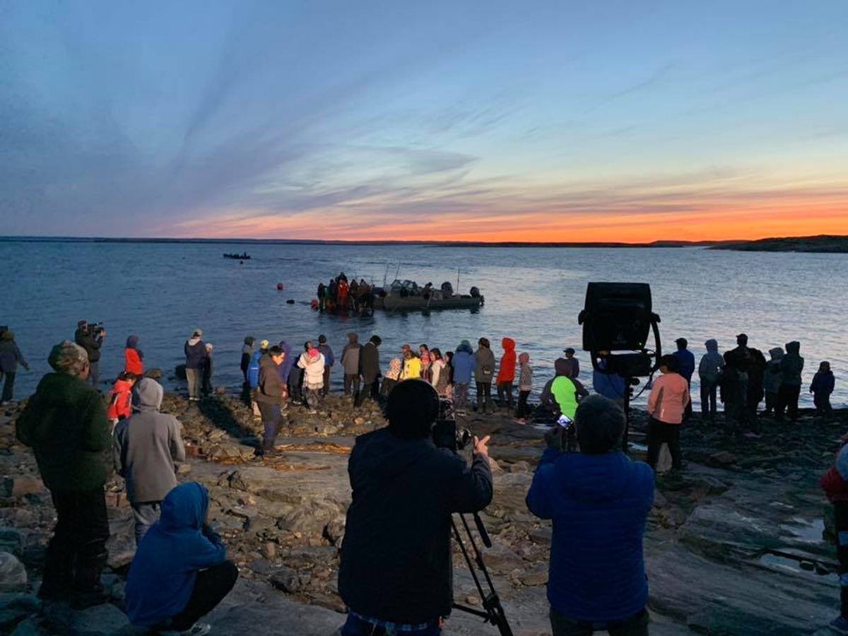 As hunters return from a bowhead hunt, community members and the film crew gather to watch.