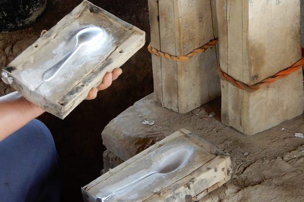 When the melted aluminum solidifies inside the wooden mold, the spoon maker pries it open, and removes the spoon.