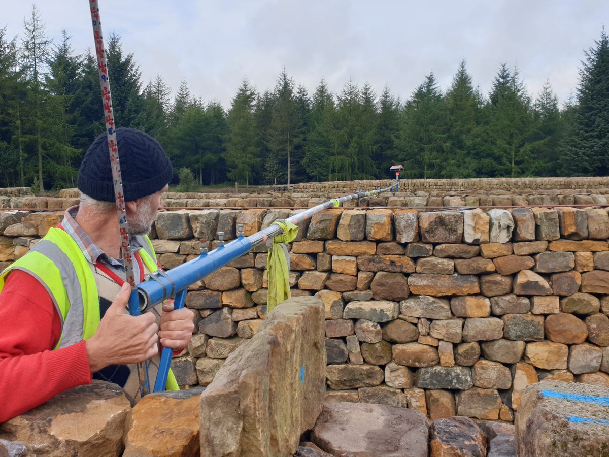 Maze designer Mark Ellis measures the inner walls to ensure they are all the same height.