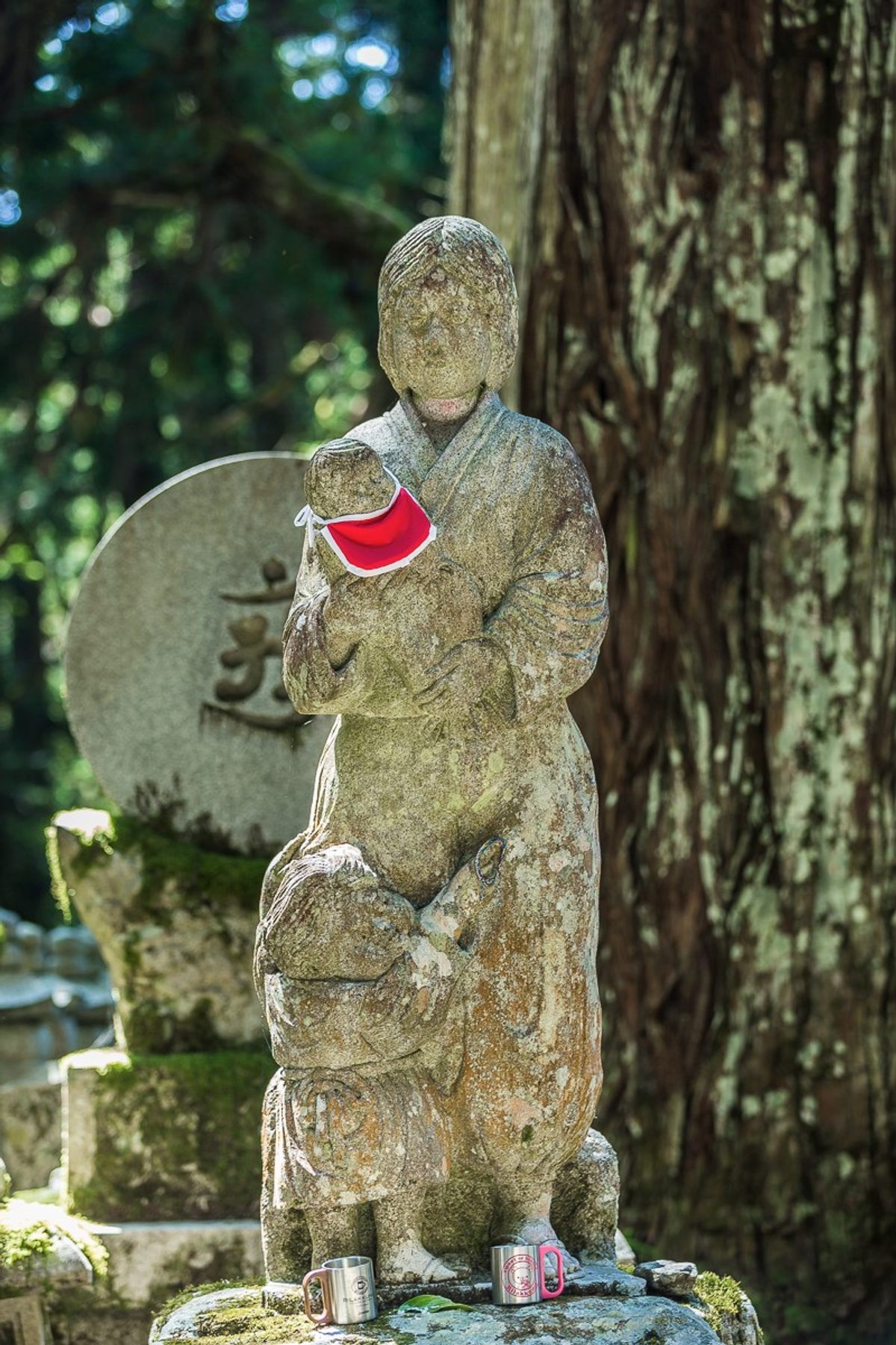 A female <em>Mizuka Jizo</em>, with an infant in arms and a child clutching at the robe.