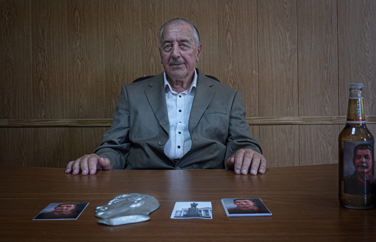 Valeri Sukhushvili sits inside the university he founded, showing off a bottle of chacha (Georgian liquor) decorated with Stalin's portrait.