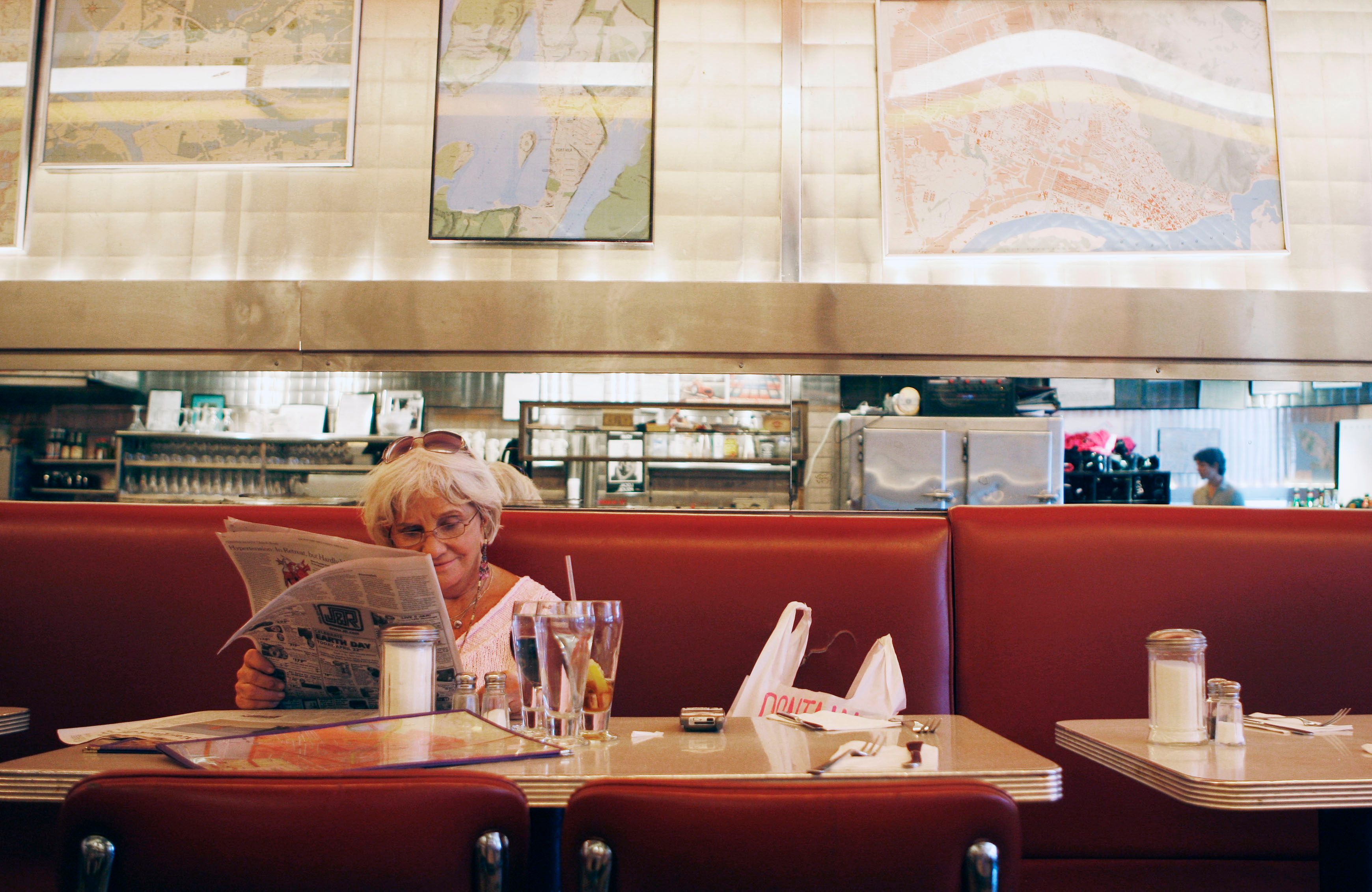 Marta Mooney reads the newspaper while sitting at Florent.