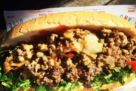 A classic chopped cheese with ground beef, melted cheese, tomato, onion, and lettuce.
