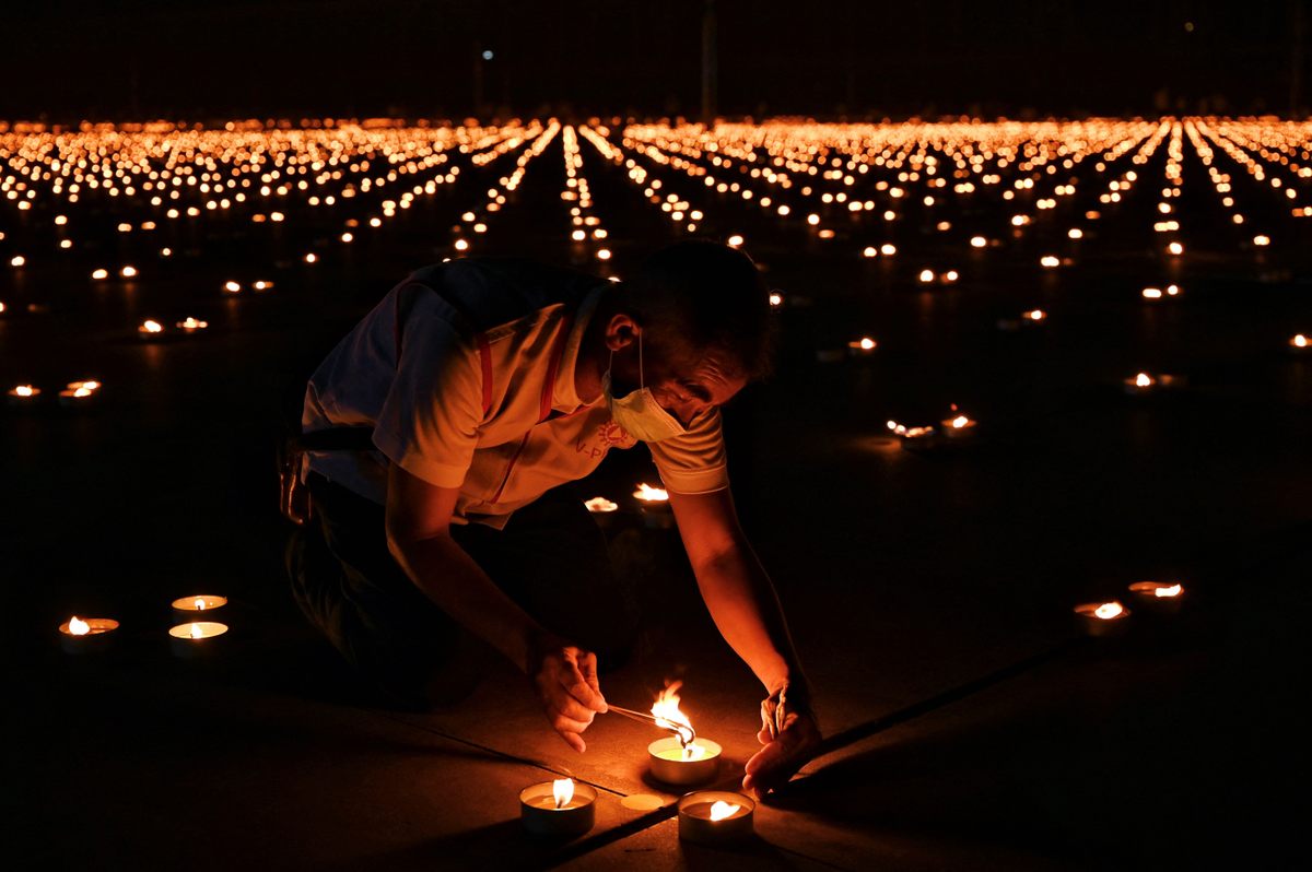 A Buddhist devotee lights a candle in an attempt to break the Guinness World Record for the largest flaming image (with somewhere between 250,000 and 330,000 candles) during Earth Day celebrations at the Wat Dhammakaya Buddhist temple on the outskirts of Bangkok on April 22, 2021. 
