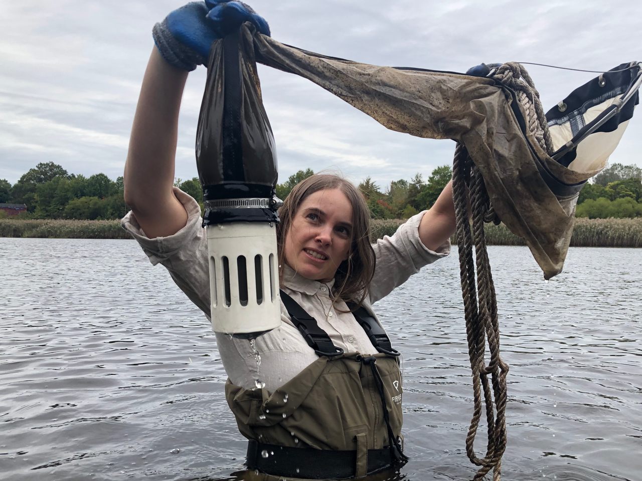 Sally Warring holds up her plankton net, teeming with microbes.