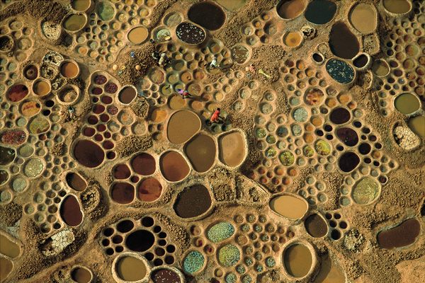 From his paraglider, Steinmetz appears to have captured a colorful, abstract mosaic made up of round tiles. In fact, these are shallow basins lined with mud, about three to five feet wide and made by hand, holding salt water that slowly evaporates to yield mineral solids, which are sold to be consumed by livestock. The colors depend on the mix of mud, algae, and salt. Teguidda-n-Tessoumt, Niger. 