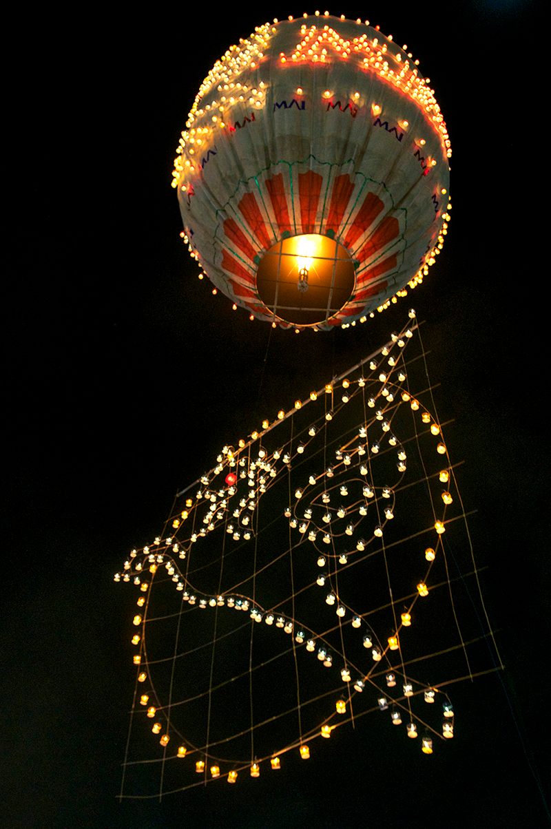 A hot-air balloon floats gently up, carrying a tail decorated with lit candles. Candle balloons are not as popular as the ones with homemade fireworks.