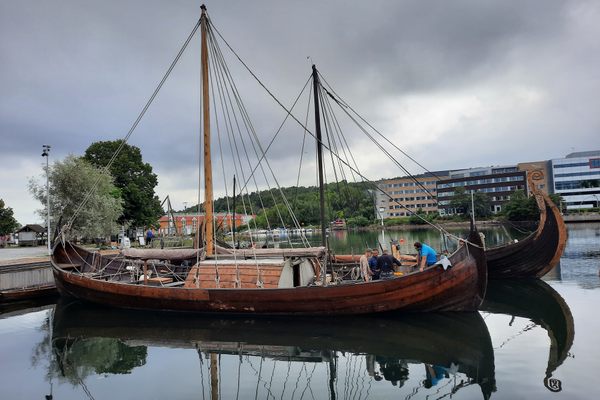 Two Viking-style sailing ships sit in a harbor.