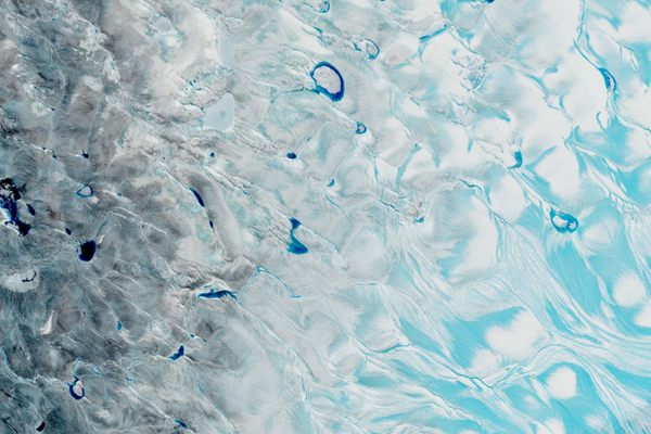 In a satellite image of the Greenland Ice Sheet's southwestern corner, captured on August 21, 2021, pale blue meltwater streams across ice or collects in slushy depressions. The deeper blue areas are meltwater lakes with depths up to about 30 feet.