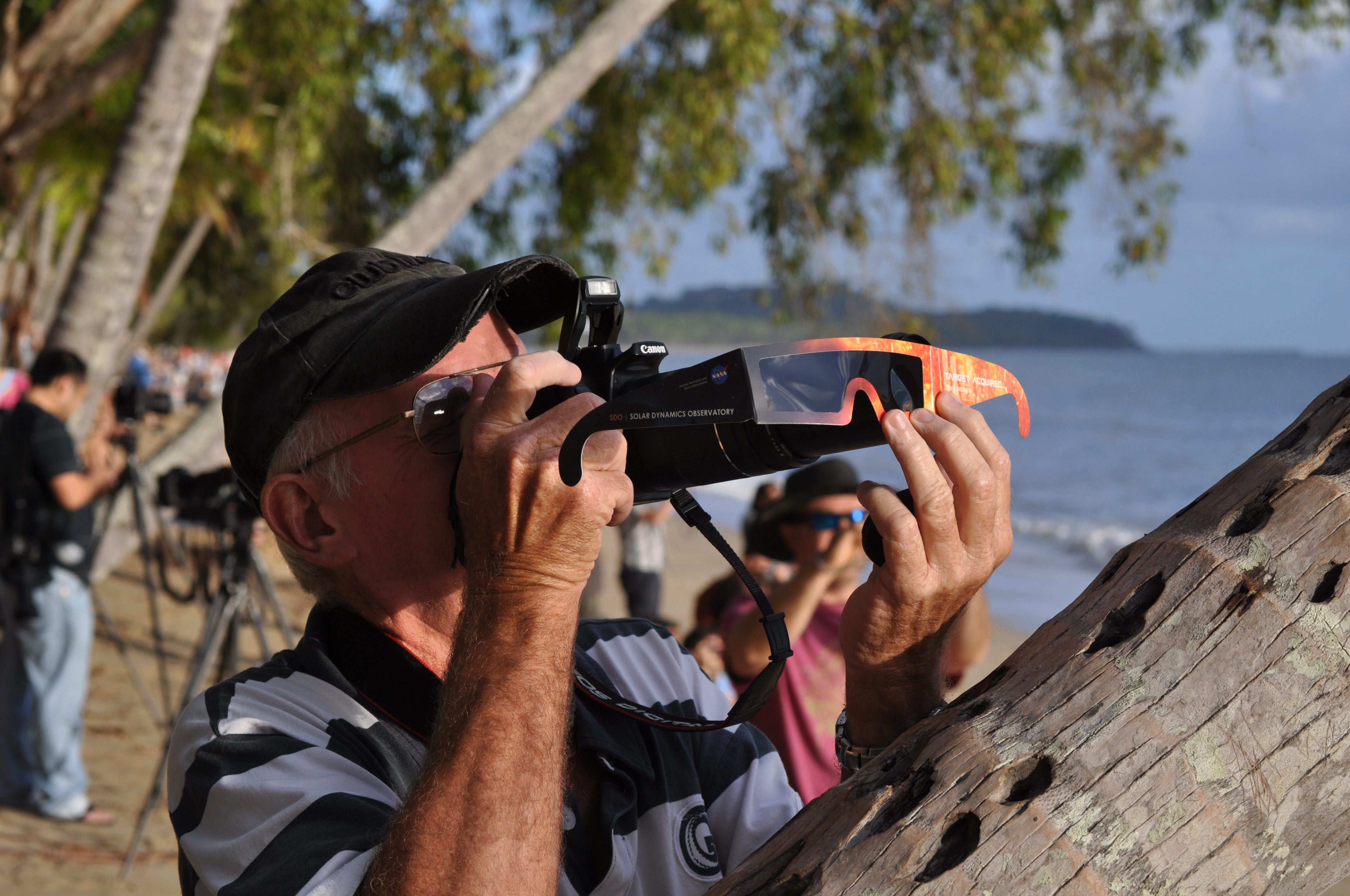 An eclipse chaser holds his special viewing glasses up to a camera during the Australian eclipse.