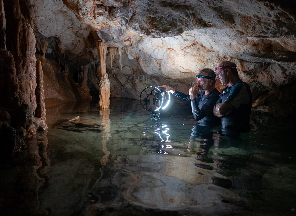 Chazaly (left) and another team member discuss how best to position scanners and other equipment in a partially-submerged chamber.