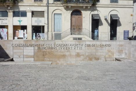 The inscription is on a wall in front of Maison Carrée.