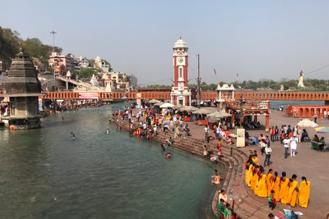 A river winds along paved banks lined with pilgrims.