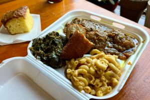 A plate with oxtails, collards, mac n' cheese, and hot water cornbread.