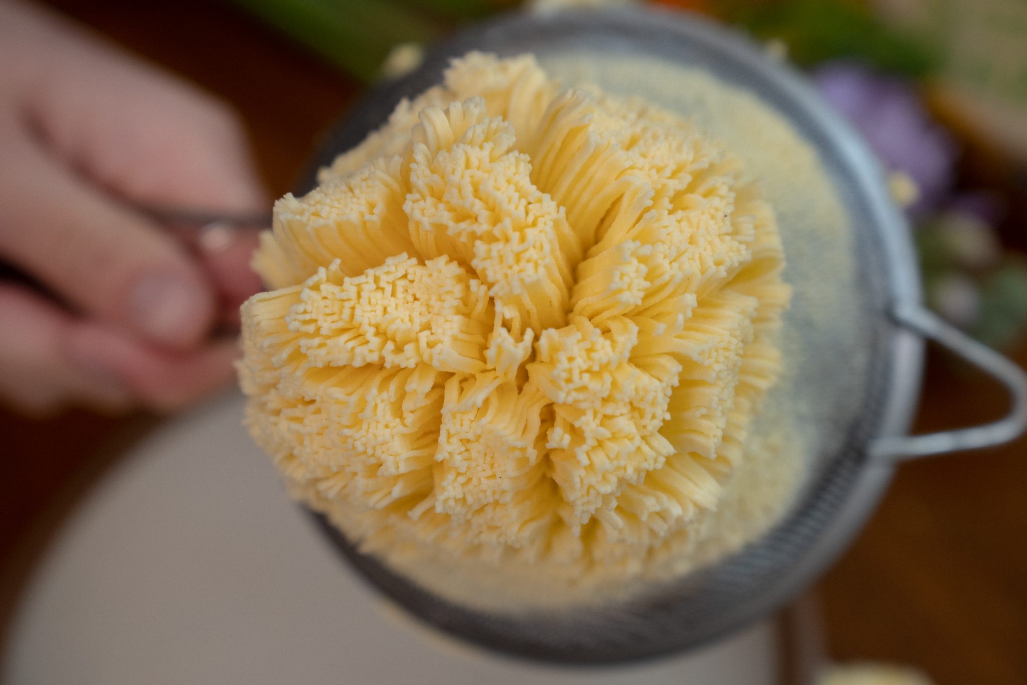 Pressing the butter through a strainer produces thin golden strings.