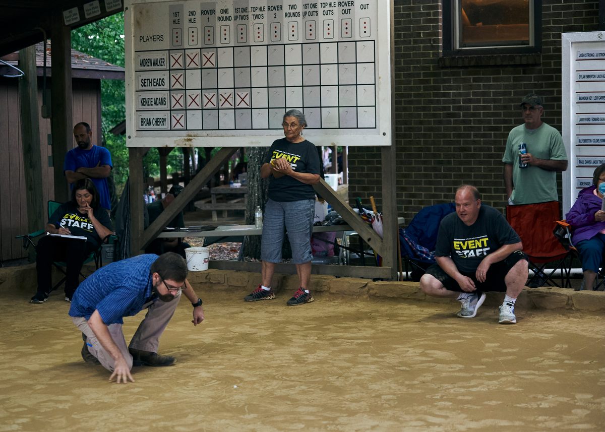 In rolley hole, two teams of two people compete to sink their marbles into three small holes in the middle of the marble yard 12 times in a prescribed order.