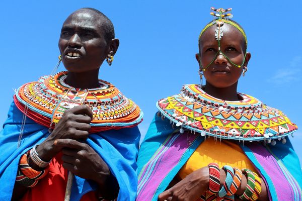 Two women pose wearing their intricate mporo necklaces.