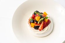 The pavlova comes crowned with jewel-like fruit.