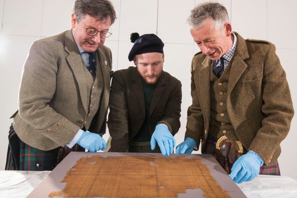 John McLeish, chair of the Scottish Tartans Authority; curator James Wylie; and Peter MacDonald (right), STA tartan historian (left to right), examine the Glen Affric tartan. 