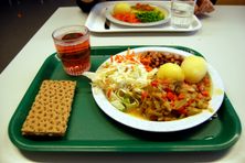 This Swedish school lunch features potatoes and other vegetables, juice, and a knäckebröd cracker.