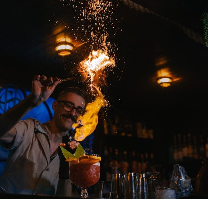 A bartender lights up a Shattered Skull cocktail at the Sunken Harbor Club.