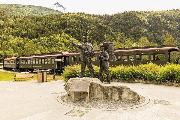 Skagway Centennial statue with the train in the background.