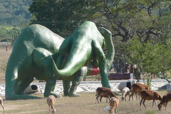 Animals graze below the massive dinosaurs.