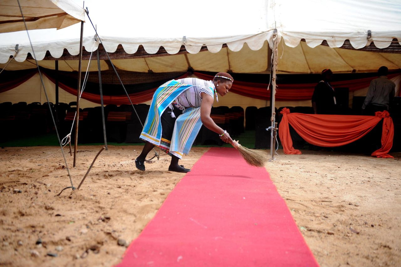 A woman sweeps the red carpet for the annual traditional ceremony for summoning the rains at Queen Modjadji's palace, Limpopo, South Africa, October 13, 2012. 