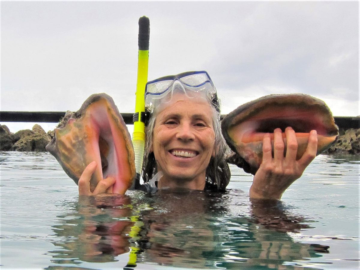 Davis, shown here holding queen conch shells at the Curaçao Sea Aquarium, has helped establish several conch farms and hatcheries around the Caribbean.