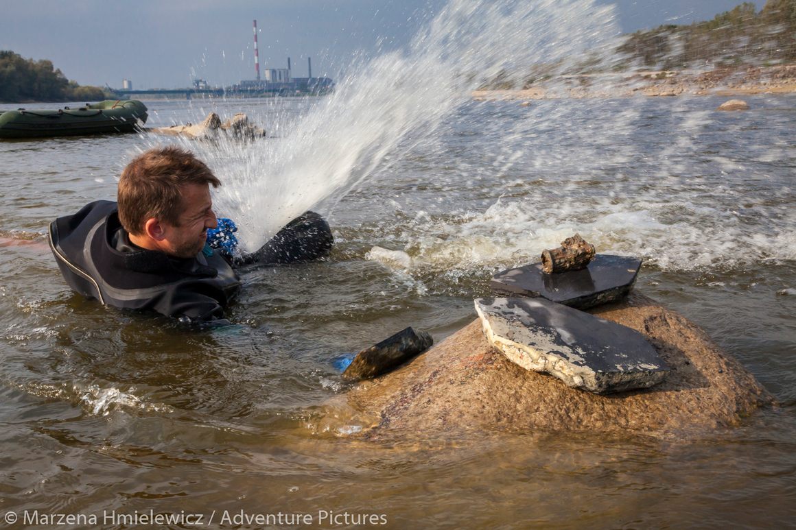 Marcin Jamkowski working with firefighters' pump to recover marble floor tiles from the riverbed