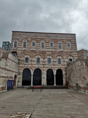 A three story outer wall with arches on the first floor and alternating white and red stonework.